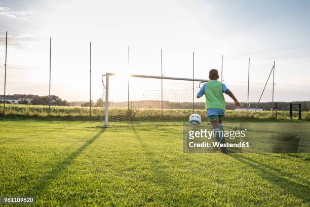 young football player on football ground at sunset - scoring a goal stock-fotos und bilder