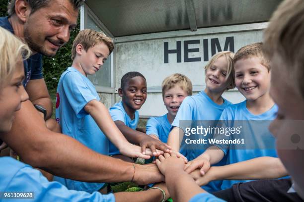 coach and young football players huddling - football player stock-fotos und bilder