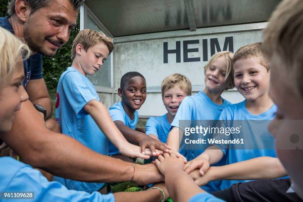 coach and young football players huddling - children football stockfoto's en -beelden