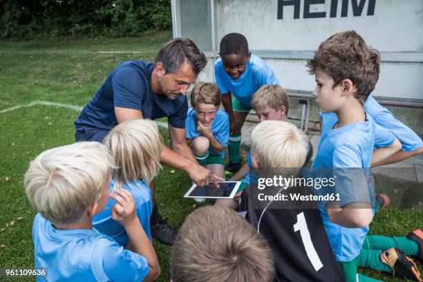 coach with tablet and young football players on football ground - local soccer field stock pictures, royalty-free photos & images