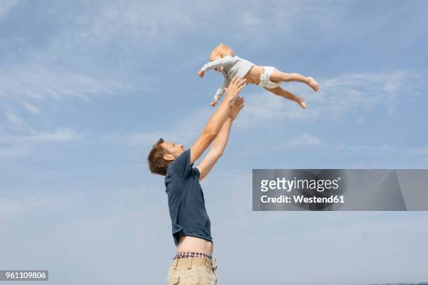 germany, timmendorfer strand, father throwing son in the air - dad throwing kid in air stockfoto's en -beelden