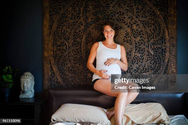 portrait of happy woman touching belly while sitting on head rest - repose tête photos et images de collection