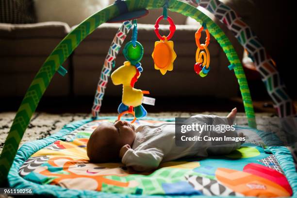 baby girl lying on playmat at home - using mobile stockfoto's en -beelden