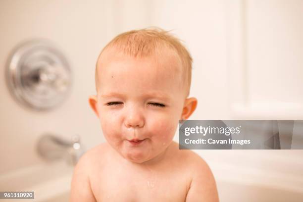 close-up of cute baby girl in bathtub - bébé grimace photos et images de collection