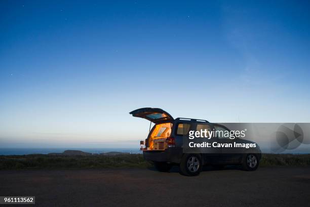sports utility vehicle parked on field against clear sky during dusk - open sky stockfoto's en -beelden