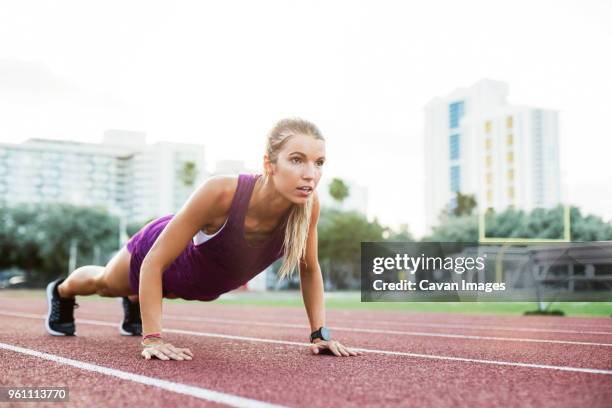 determined female athlete doing push-ups on race tracks - center athlete stock pictures, royalty-free photos & images