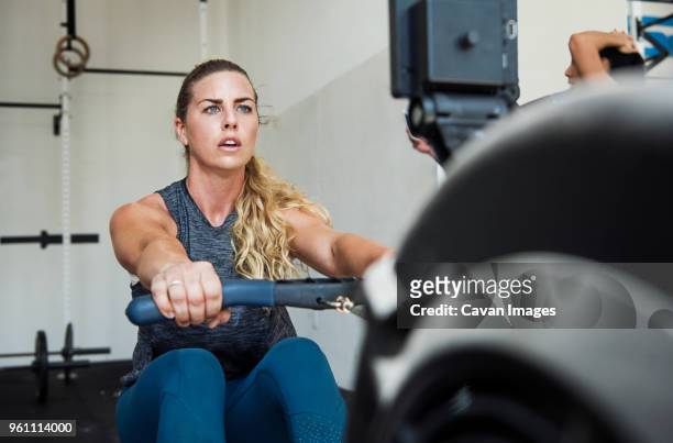 focused athlete exercising on rowing machine in gym gym - rowing machine stock pictures, royalty-free photos & images