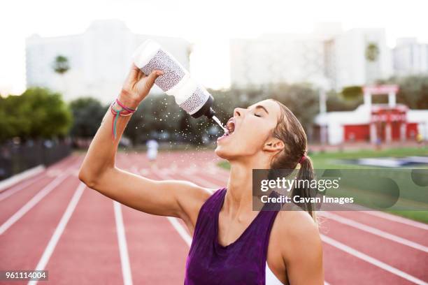 female athlete drinking water on race tracks - bottle water sport stock-fotos und bilder