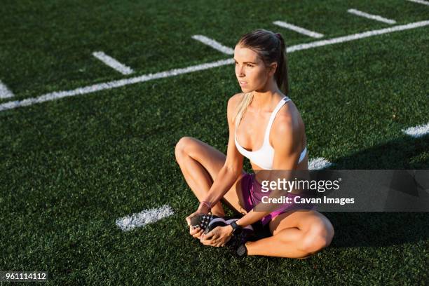 high angle view of female athlete performing short adductor stretch on field - escote fotografías e imágenes de stock