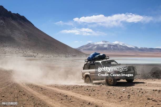 off-road vehicle moving on dirt road against sky during sunny day - schotterstrecke stock-fotos und bilder