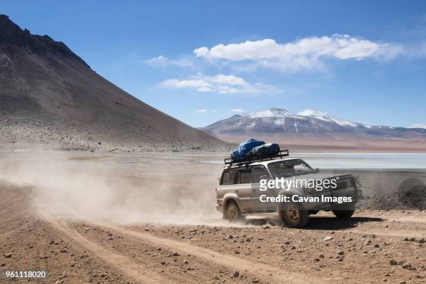 off-road vehicle moving on dirt road against sky during sunny day - atv trail stock pictures, royalty-free photos & images