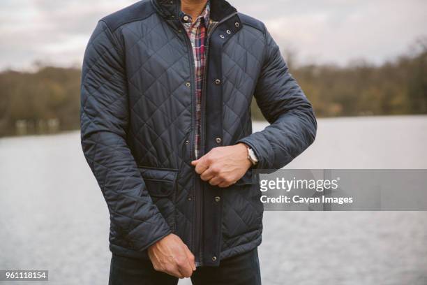 midsection of man zipping leather jacket while standing by lake against sky in forest - zipper stock pictures, royalty-free photos & images