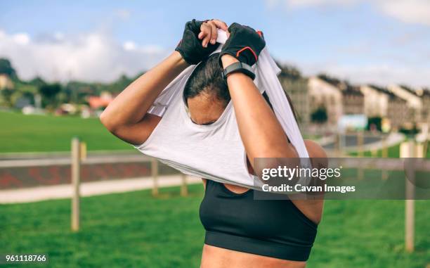 sportswoman taking off t-shirt at park - entkleiden stock-fotos und bilder