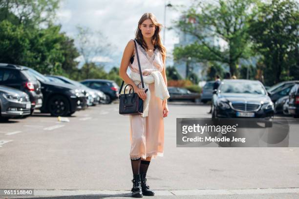 Dutch model Vera Van Erp wears a pink slip dress with a white knit sweater tied around her waist, black socks, black Balenciaga buckle boots, and a...