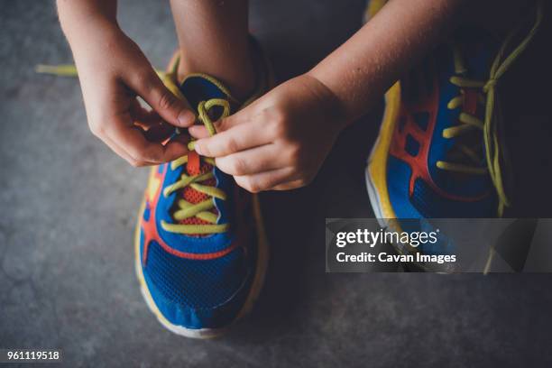 cropped hands of boy tying shoelace - tied up 個照片及圖片檔