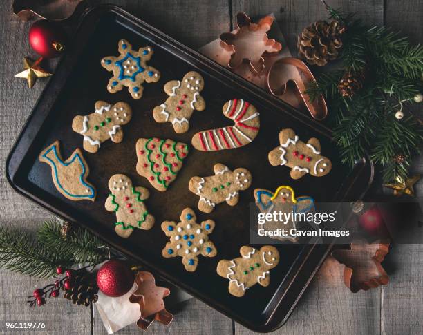 overhead view of gingerbread cookies in baking sheet by pastry cutters on table - tablett oder küchenblech stock-fotos und bilder