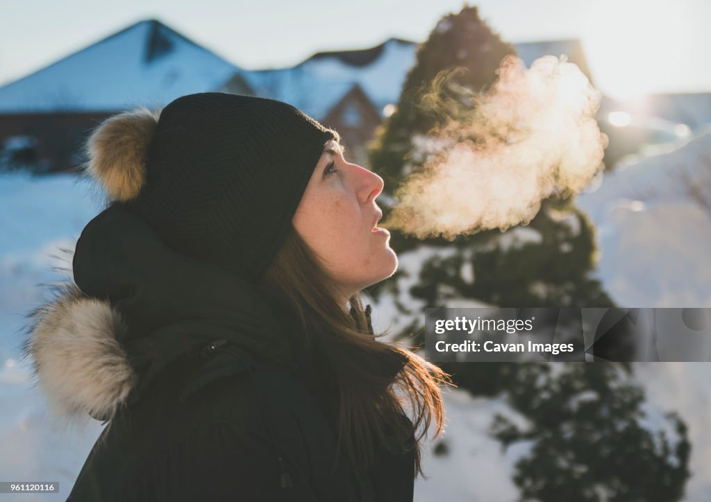 Side view of woman exhaling breath vapor during winter