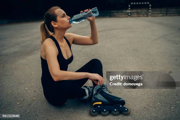 mulher bebendo água e relaxar depois de patins em linha - inline skating - fotografias e filmes do acervo