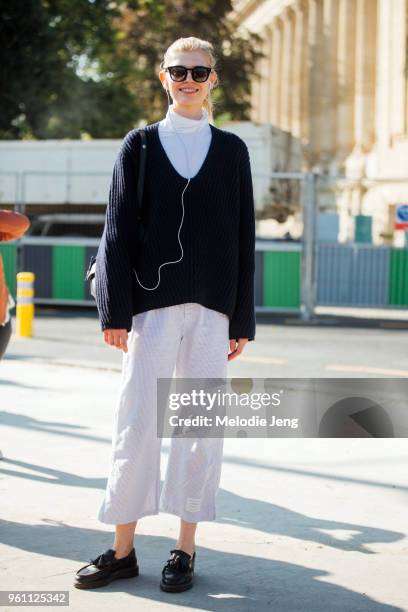 Polish model Ola Rudnicka listens to music and wears an oversized blue sweater over a white turtleneck, white capri pants, and black shoes after the...