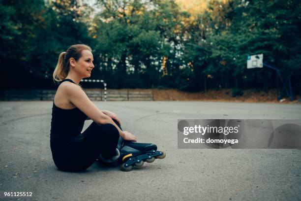 woman taking a rest after hard exercise and inline skating outdoors - work hard play hard stock pictures, royalty-free photos & images