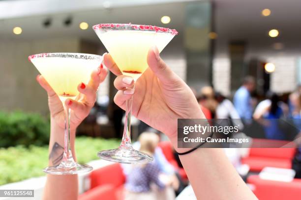 cropped hands of female friends toasting martini glasses at restaurant - cocktail glass salt stock pictures, royalty-free photos & images