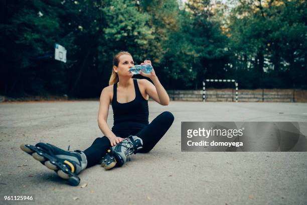 woman taking a rest after hard exercise and inline skating outdoors - work hard play hard stock pictures, royalty-free photos & images