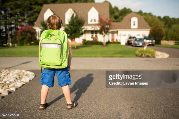rear view of schoolboy with backpack standing on street during sunny day - one boy stock pictures, royalty-free photos & images