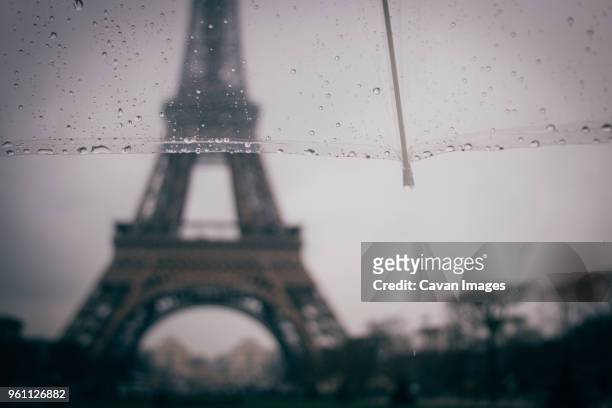 cropped image of umbrella against eiffel tower during rainy season - tourism drop in paris foto e immagini stock