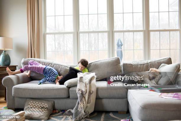 siblings on sofa at home - messy dog stockfoto's en -beelden