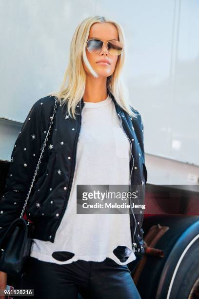 Swedish model Frida Aasen wears reflective sunglasses, a black embellished jacket, and white distressed top after the Miu Miu show at Palais d'Iena...