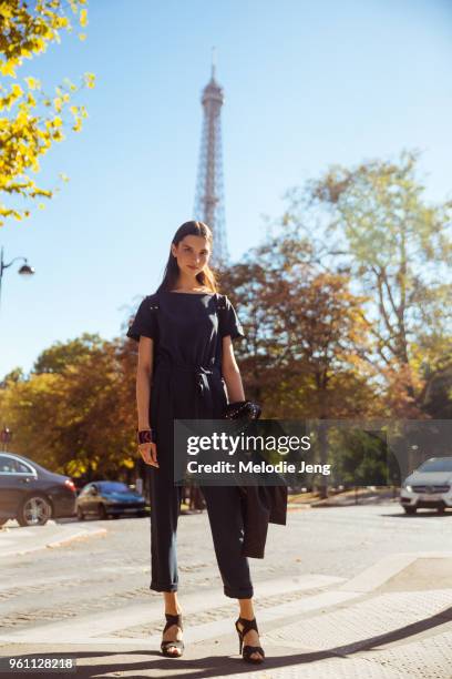 Model Anastasia Chekry wears a dark jumpsuit, bracelet, and heels, and poses in front of the Eiffel Tower after the Miu Miu show at Palais d'Iena on...