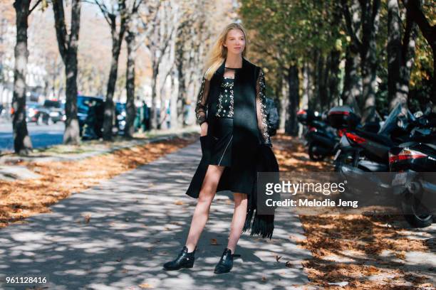 Model Piene Burgers wears a black jacket and top with lace floral embellished sleeve, a black short skirt, and black boots after the Moncler Gamme...