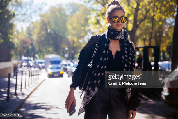 Taylor Hill wears yellow reflective sunglasses, a printed scarf, and black outfit after the Miu Miu show at Palais d'Iena on October 05, 2016 in...