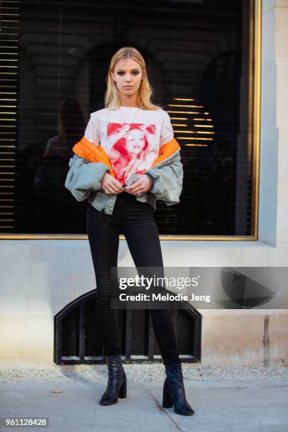 Danish model Ulrikke Hoyer wears a green bomber jacket off her shoulders, a t-shirt with a photograph, black jeans, and black boots after the Louis...