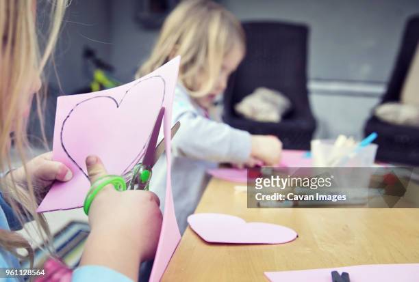 sisters making valentine greeting card at home - child cutting card stock pictures, royalty-free photos & images