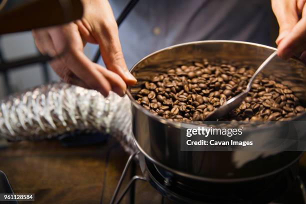 midsection of man roasting coffee beans in machinery at cafe - coffee manufacturing stock pictures, royalty-free photos & images