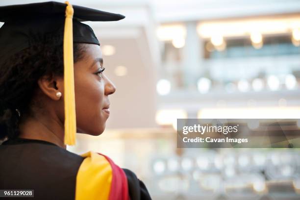 woman in graduation gown looking away - graduation clothing stockfoto's en -beelden