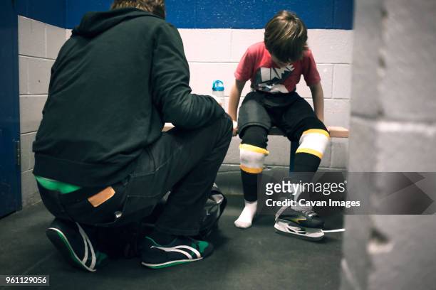 father helping son with ice skates - genderblend2015 stock pictures, royalty-free photos & images