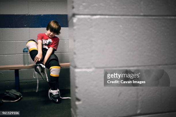 boy putting on ice hockey skates - hockey su ghiaccio foto e immagini stock