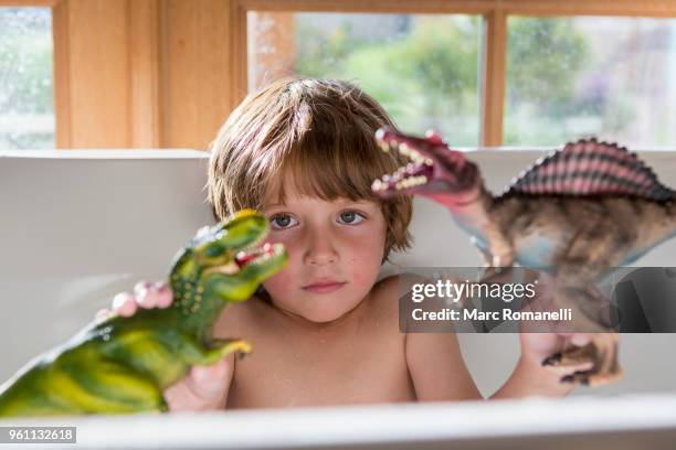 4 year old boy in bathtub playing with toy dinosaurs - lamy new mexico stock pictures, royalty-free photos & images