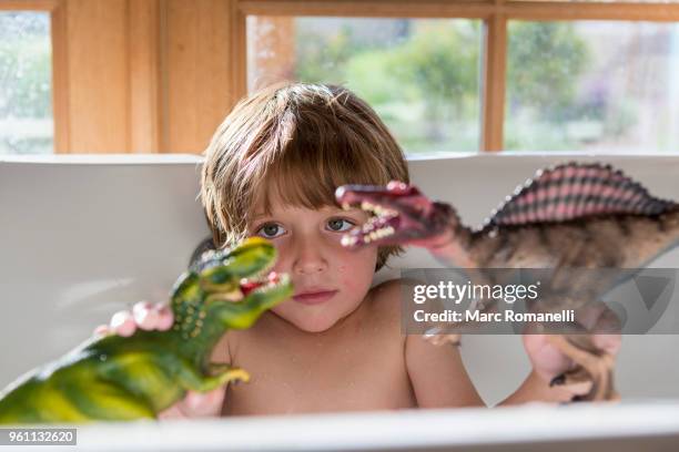 4 year old boy in bathtub playing with toy dinosaurs - lamy new mexico stock pictures, royalty-free photos & images