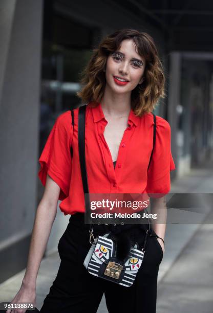 Model Karime Bribiesca wears "Perfectly Imperfect" eye makeup from a show, a red shirt, black pants, and Furla face bag during New York Fashion Week...