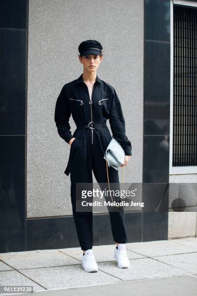 Model Mckenna Hellam wears a black conductor cap, 3.1 Phillip Lim black jumpsuit, teal bag, and white Reebok sneakers during New York Fashion Week...