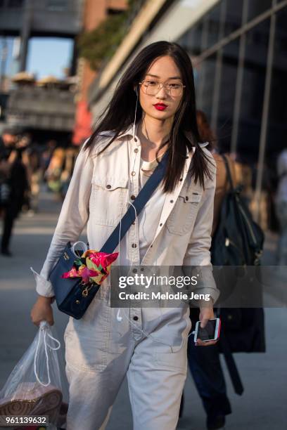 Model Hyun Ji Shin wears thin frame glasses, a white jumpsuit, and blue Prada bag during New York Fashion Week Spring/Summer 2018 on September 10,...