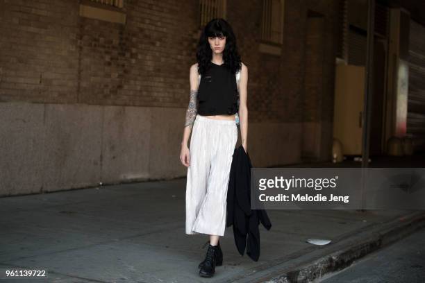 Model Makenna Cart wears a distressed black top, loose white pleated cropped pants, and black boots during New York Fashion Week Spring/Summer 2018...