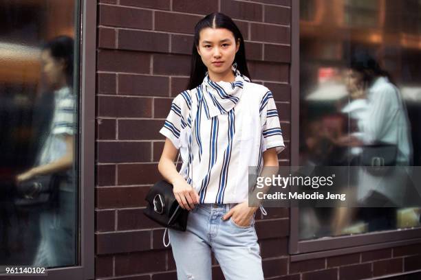 Model Estelle Chen in a blue and white stripe shirt and black paperclip bag after the 3.1 Phillip Lim show during New York Fashion Week Spring/Summer...