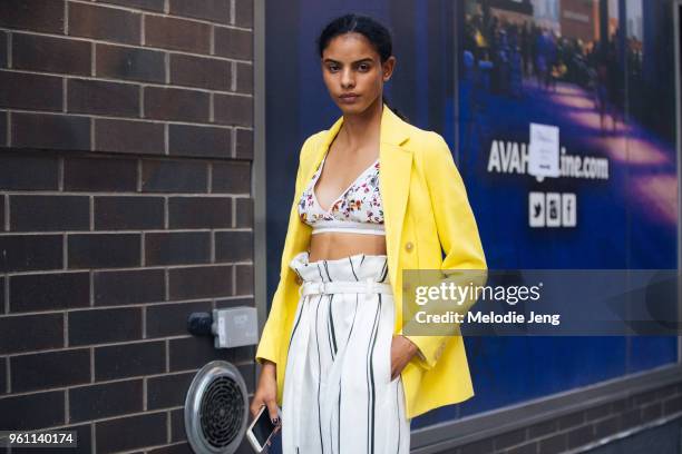 Model Mileshka Cortes wears a yellow blazer and 3.1 Phillip Lim floral bra and white striped pants during New York Fashion Week Spring/Summer 2018 on...