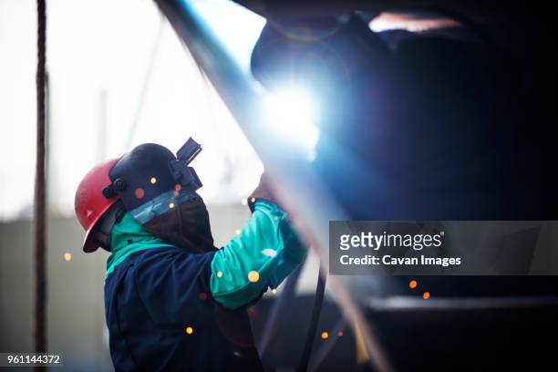 side view of worker welding container ship at industry - scheepsbouwer stockfoto's en -beelden