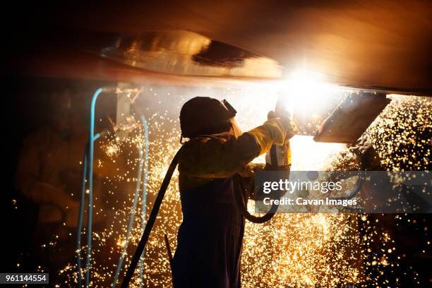 side view of worker welding airplane wing at night - aircraft mechanic stock-fotos und bilder