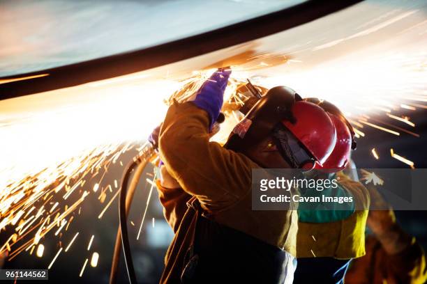 workers welding airplane wing at industry during night - metallindustrie stock-fotos und bilder